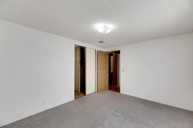 empty room with a textured ceiling and carpet floors