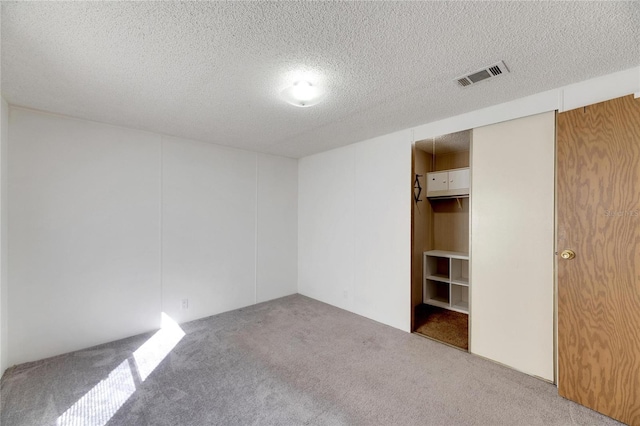 empty room with light colored carpet and a textured ceiling