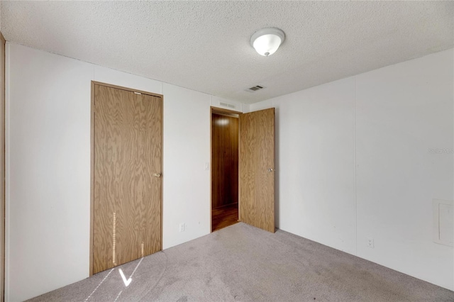 unfurnished bedroom with a closet, carpet, and a textured ceiling