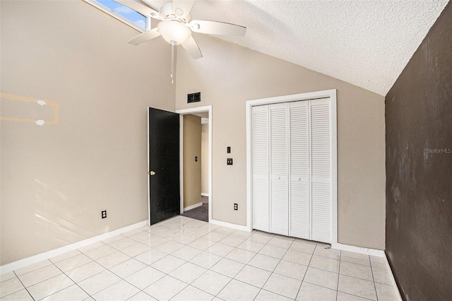 unfurnished bedroom with high vaulted ceiling, ceiling fan, light tile patterned floors, a textured ceiling, and a closet