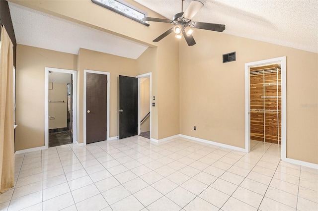 unfurnished bedroom featuring a textured ceiling, ensuite bath, a spacious closet, and ceiling fan