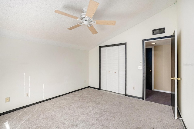 unfurnished bedroom with vaulted ceiling, carpet flooring, ceiling fan, a textured ceiling, and a closet