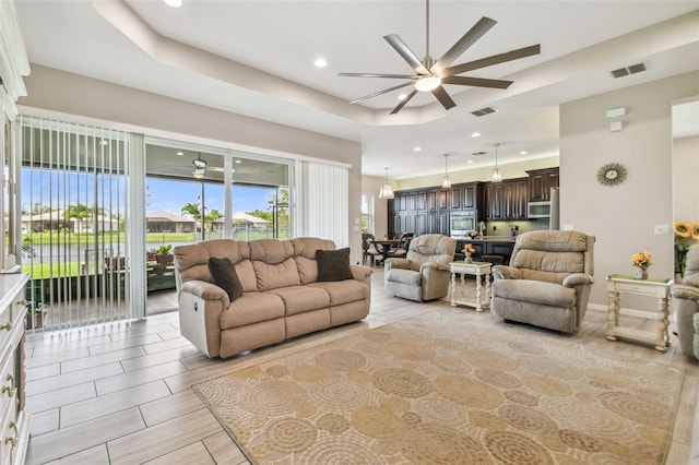 living room with a raised ceiling and ceiling fan