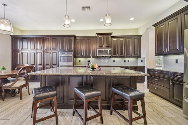 kitchen featuring light stone countertops, hanging light fixtures, and appliances with stainless steel finishes