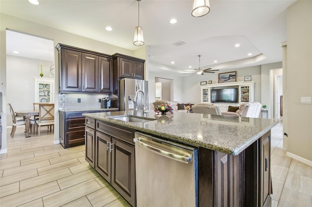 kitchen featuring dark brown cabinets, sink, an island with sink, and appliances with stainless steel finishes