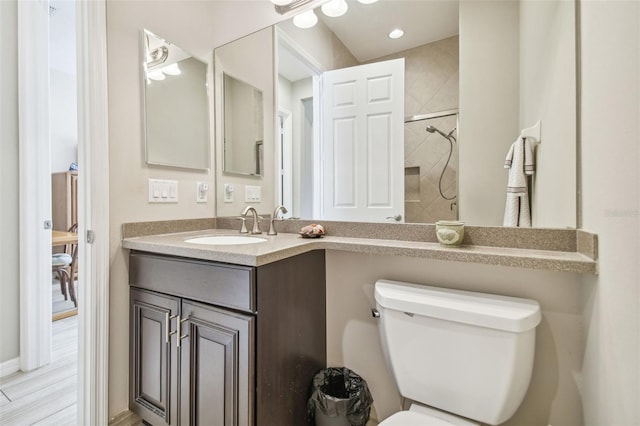 bathroom with a tile shower, vanity, and toilet