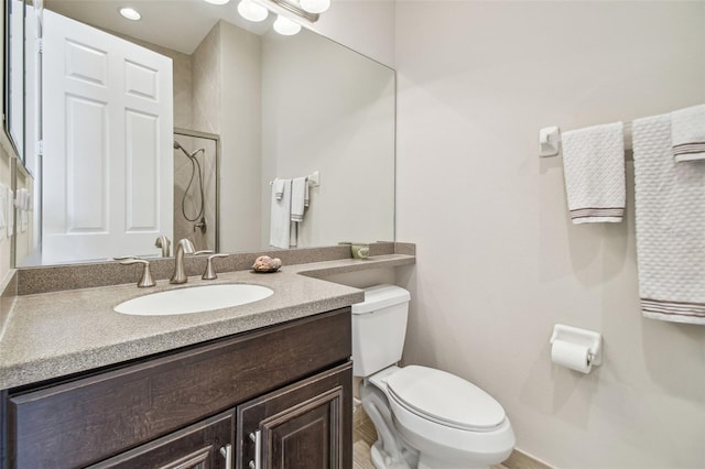 bathroom with tiled shower, vanity, and toilet