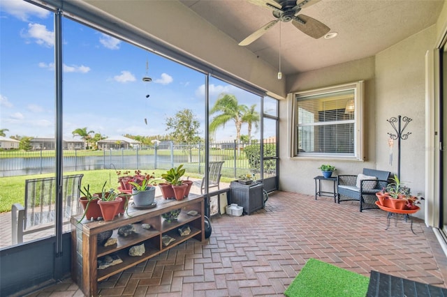 sunroom featuring ceiling fan and a water view