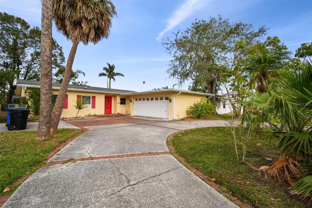 918 Snell Isle Blvd NE, Saint Petersburg, FL 33704 - ranch-style house with stucco siding, driveway, a garage, and a front lawn