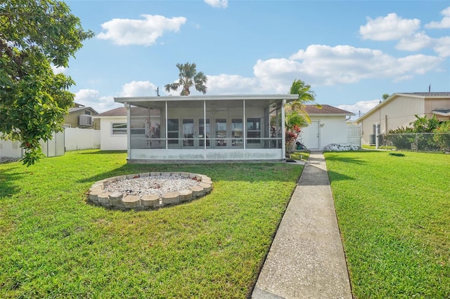 rear view of property with a sunroom, an AC wall unit, and a lawn