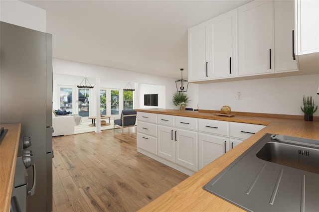 kitchen with white cabinets, decorative light fixtures, and butcher block countertops