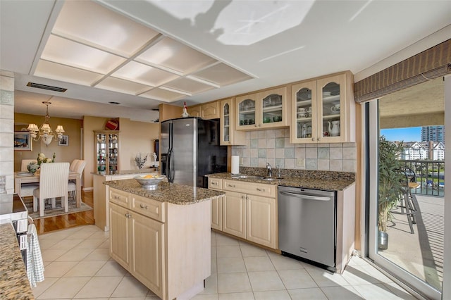 kitchen with light stone countertops, tasteful backsplash, stainless steel appliances, light brown cabinets, and a kitchen island