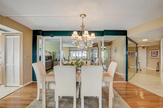 dining area with hardwood / wood-style floors, a textured ceiling, and an inviting chandelier