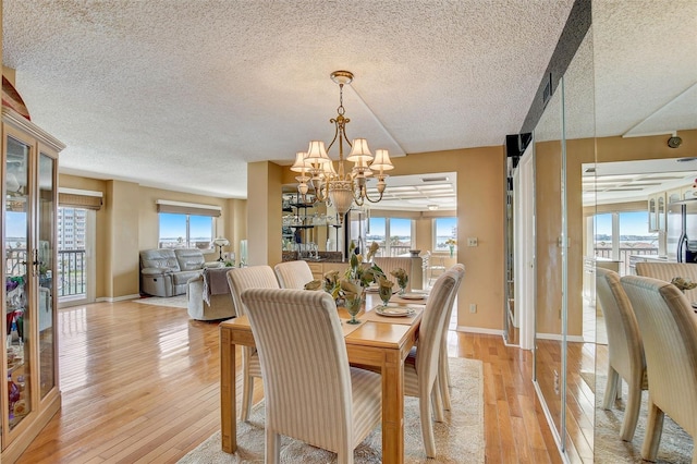 1651 Sand Key Estates Ct Unit 52, Clearwater, FL 33767 - dining area featuring a textured ceiling, a chandelier, healthy amount of natural light, light wood-style flooring, and baseboards