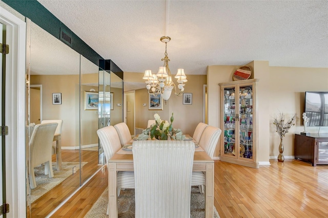 dining area with hardwood / wood-style floors, a chandelier, and a textured ceiling