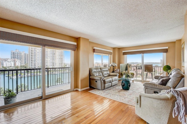 living room with light hardwood / wood-style floors, a water view, and a textured ceiling