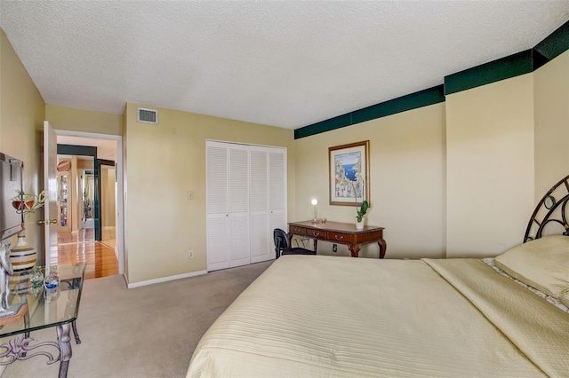 bedroom with a textured ceiling, light carpet, and a closet