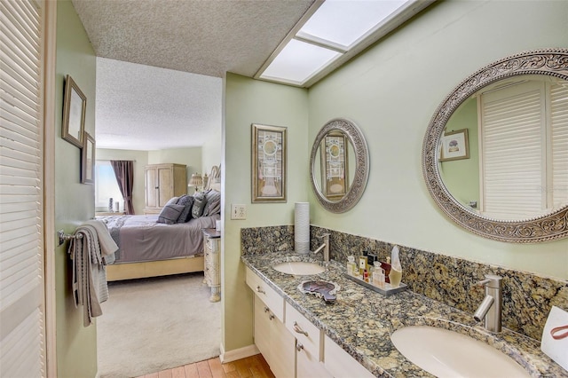 bathroom featuring vanity, wood-type flooring, a textured ceiling, and a skylight