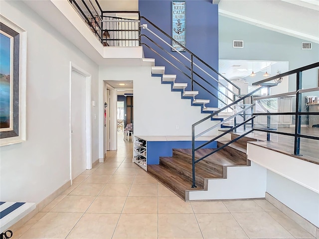 stairs featuring tile patterned floors and high vaulted ceiling