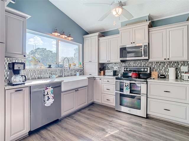 kitchen featuring appliances with stainless steel finishes, backsplash, light hardwood / wood-style flooring, and sink