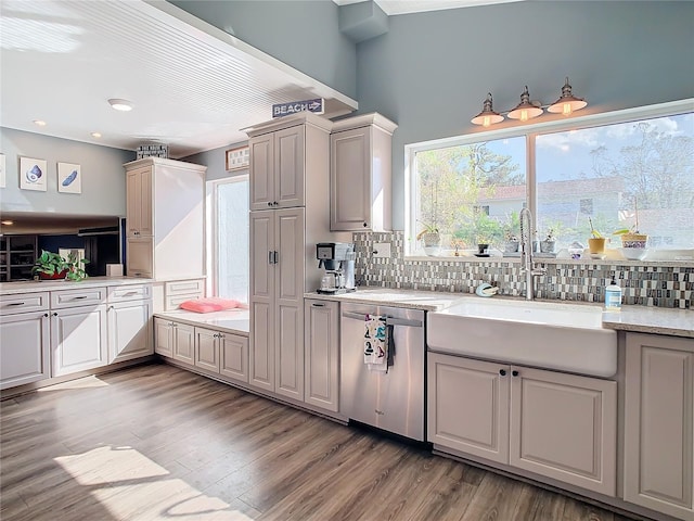 kitchen with dishwasher, decorative backsplash, light wood-type flooring, and sink