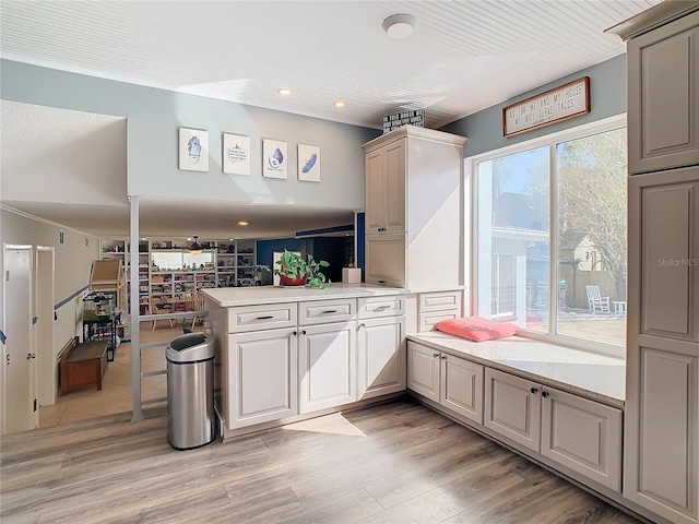 kitchen with a breakfast bar area, kitchen peninsula, light stone counters, and light wood-type flooring