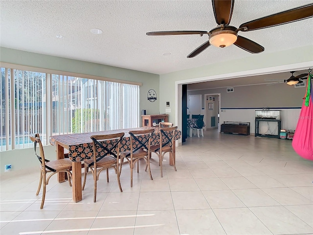 dining room with a textured ceiling, ceiling fan, and light tile patterned flooring