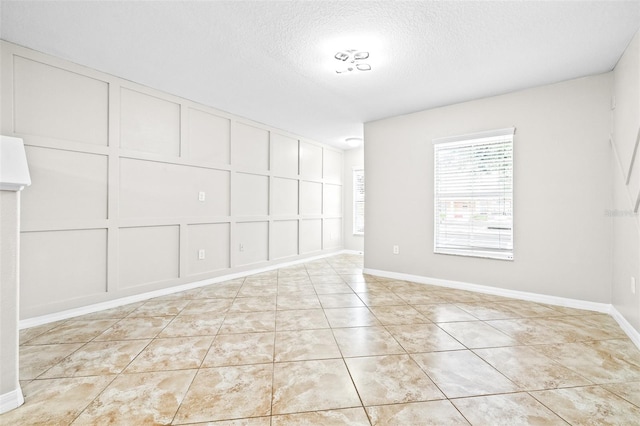 spare room featuring a textured ceiling and light tile patterned floors