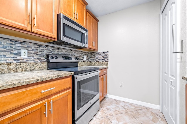 kitchen featuring stainless steel appliances, light tile patterned flooring, backsplash, and light stone counters