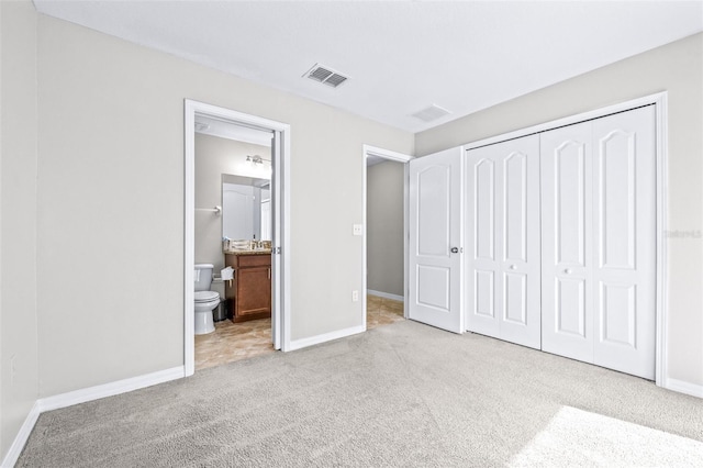 unfurnished bedroom featuring connected bathroom, a closet, and light carpet