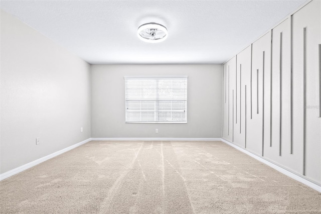 unfurnished room featuring a textured ceiling and light carpet