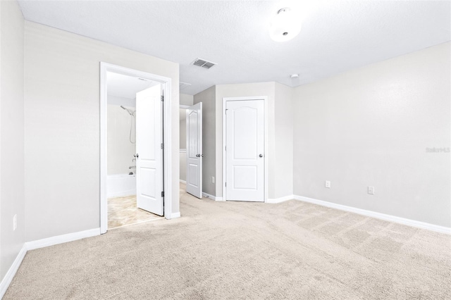 unfurnished bedroom featuring connected bathroom and light carpet