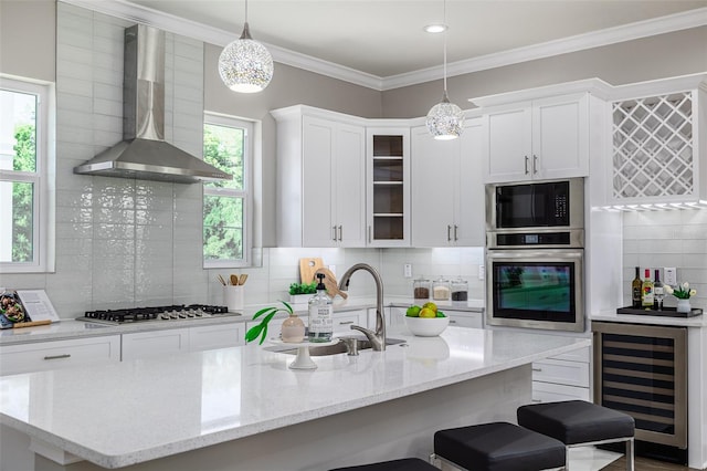 kitchen featuring stainless steel appliances, wall chimney range hood, beverage cooler, and plenty of natural light