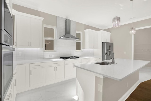 kitchen with white cabinets, wall chimney exhaust hood, a center island with sink, and appliances with stainless steel finishes