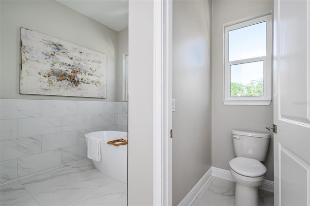 3845 Seena Manor Ct, Tampa, FL 33618 - bathroom featuring marble finish flooring, a freestanding tub, toilet, and baseboards