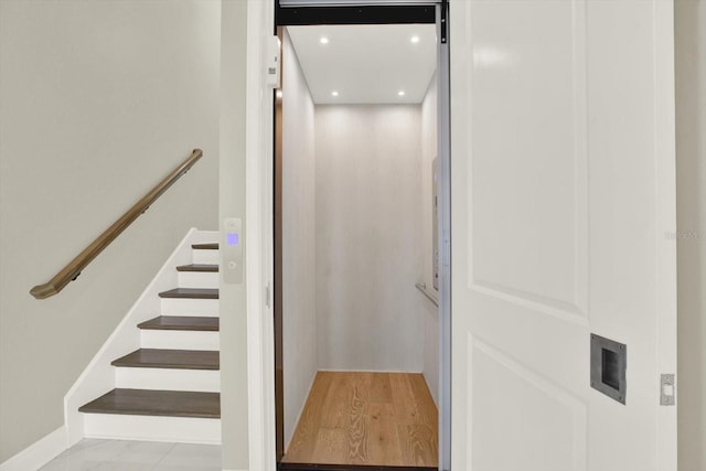 staircase with elevator and wood-type flooring