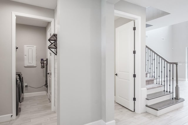 staircase with hardwood / wood-style floors, electric panel, and washer and clothes dryer