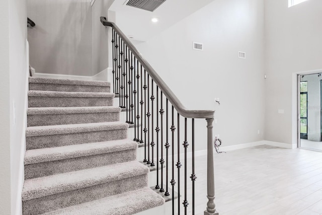 stairway with a towering ceiling and hardwood / wood-style floors