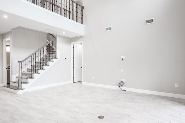 interior space with a towering ceiling and light hardwood / wood-style floors