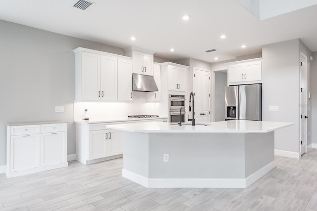 kitchen featuring stainless steel appliances, a center island with sink, sink, and white cabinets