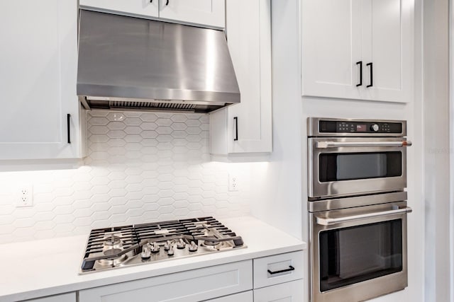 kitchen with stainless steel appliances, white cabinets, extractor fan, and tasteful backsplash