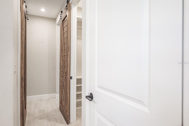 corridor featuring a barn door and light hardwood / wood-style floors