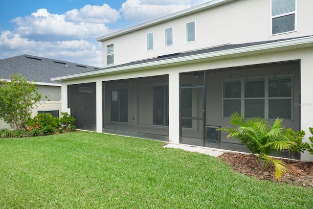 back of property with a lawn and a sunroom