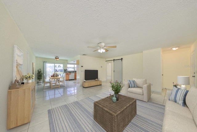 tiled living room with ceiling fan, a barn door, and a textured ceiling