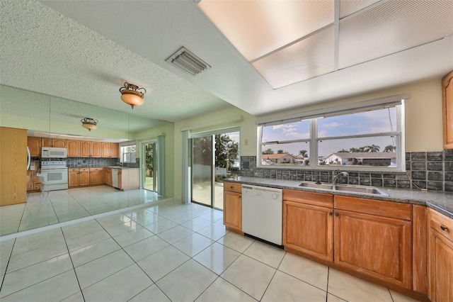 kitchen featuring decorative backsplash, light tile patterned floors, white appliances, and sink