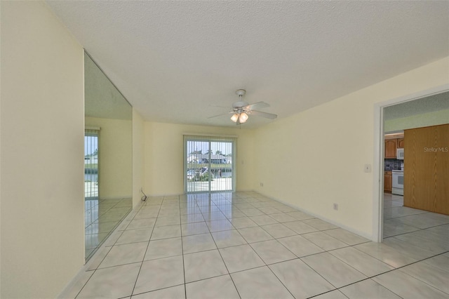 unfurnished room featuring ceiling fan, light tile patterned floors, and a textured ceiling