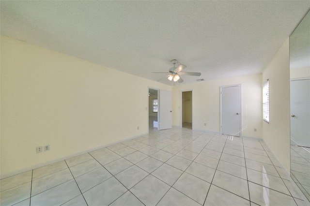 tiled spare room with ceiling fan and a textured ceiling