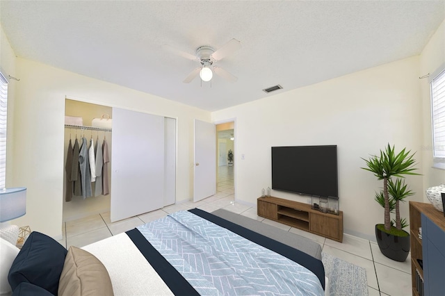 tiled bedroom with a textured ceiling, a closet, and ceiling fan