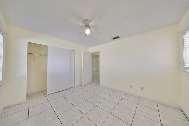 unfurnished bedroom with ceiling fan, light tile patterned flooring, and a closet