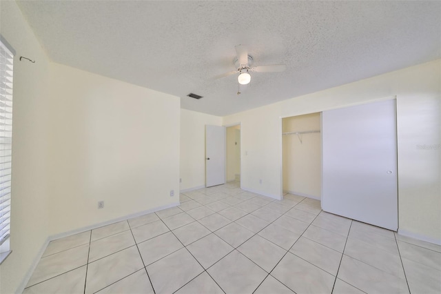 unfurnished bedroom featuring ceiling fan, light tile patterned floors, a textured ceiling, and a closet